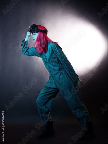 young woman with pink hair and in a jumpsuit uses virtual reality glasses, is in the game,