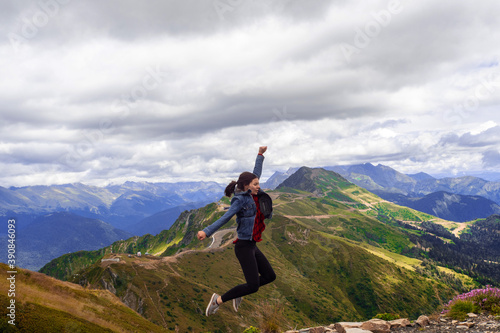 cheerful young woman after a successful Hiking fun jumps on the top of the mountain.