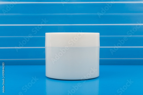 White plastic cream jar on blue background with stripes photo