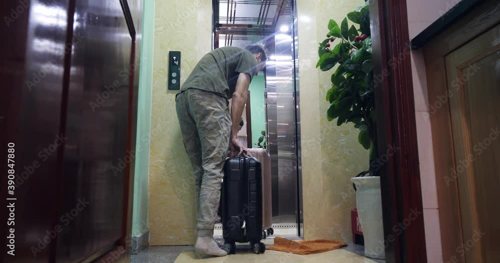 Young man in casual clothes with luggages opens and rides a hotel lfit. Young man in casual clothes with luggages opens and rides a hotel lfit.