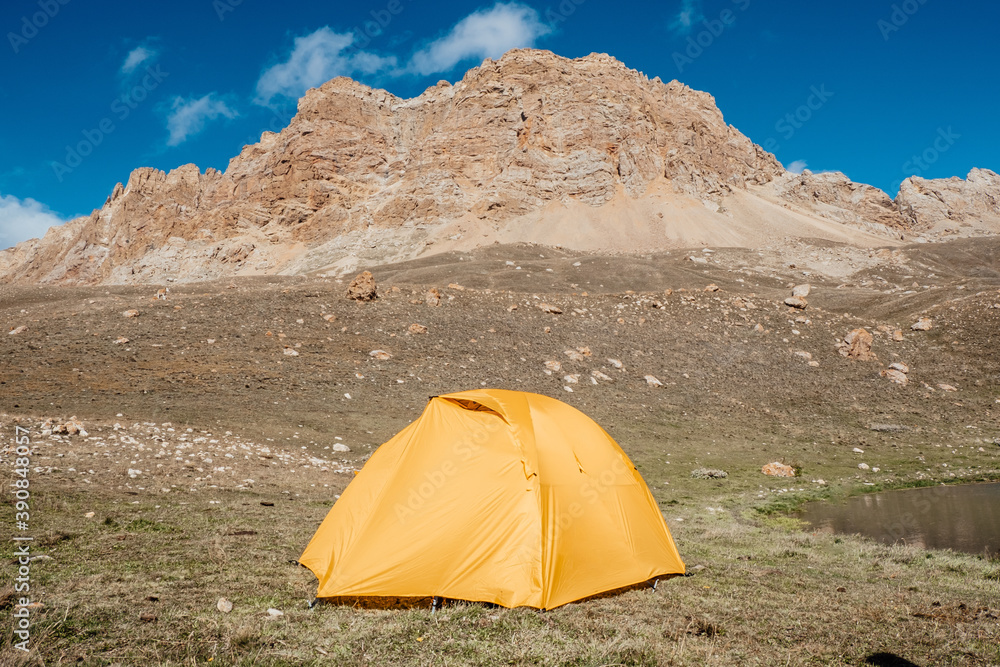 Bright yellow tourist tent in the mountains. Active lifestyle concept.