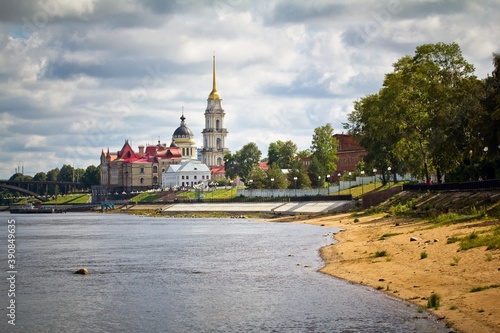 The embankment of the Volga river in the foreground, Transfiguration Cathedral and Historical museum against cloudy sky in summer in Rybinsk, Yaroslavl Oblast, Russia. photo