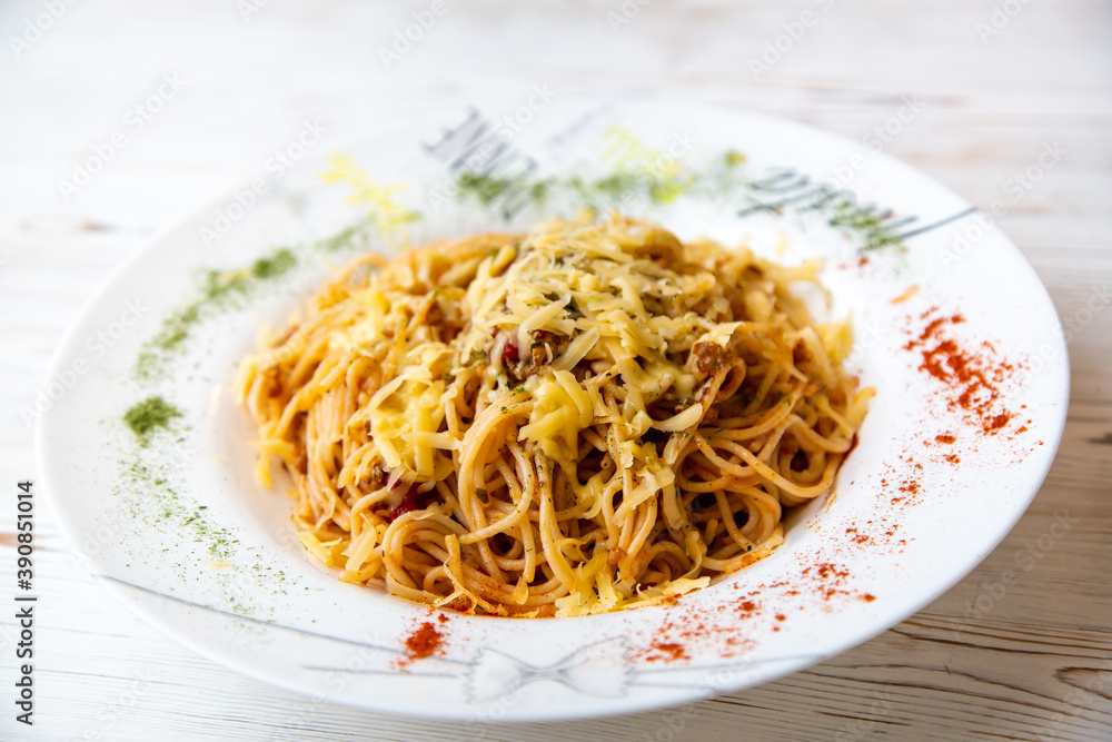 Pasta with Bolognese sauce, cheese and spices in a large white plate on a white wooden background Pasta with Bolognese sauce, cheese and spices in a large white plate on a white wooden background