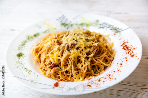 Pasta with Bolognese sauce, cheese and spices in a large white plate on a white wooden background