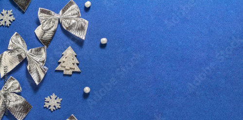 Background with Christmas silver bows, snowflakes and beads on a dark blue background. New year, Christmas. Space for text, top view