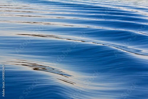 Blue water with slight waves on the surface with reflection.