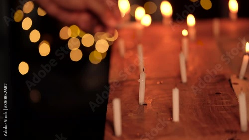 Indian man or male hand illuminating or lighting up some candles on Diwali night at a temple, church. Concept for festive decoration, holiday, Christmas celebration, religious rituals.