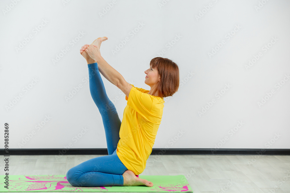 An adult woman doing yoga in a white hall. Beautiful woman doing stretching. An adult woman doing yoga in a white hall. Beautiful woman doing stretching.