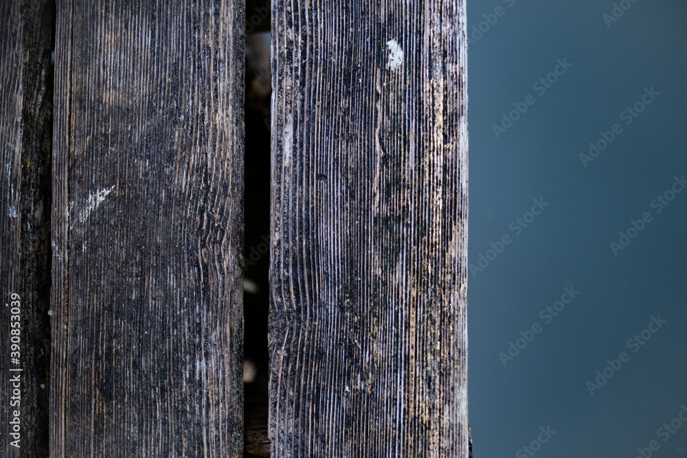 Fototapeta premium Ein abstraktes Bild eines alten Holzsteges der sich über dramatisch blauem Wasser befindet