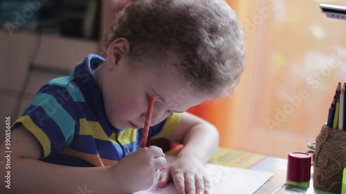 Little boy draws at a table at home. The child is engaged in creativity, studying at home, video