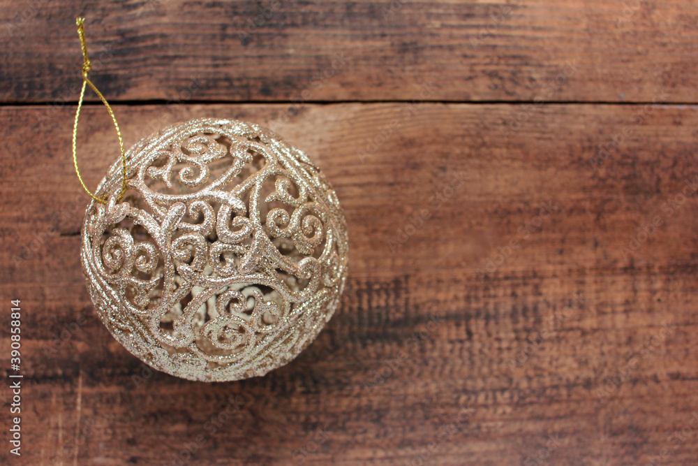Golden fishnet Christmas ball on wooden background. Top view of luxury Christmas ornament on wood table. Retro style Golden fishnet Christmas ball on wooden background. Top view of luxury Christmas ornament on wood table. Retro style
