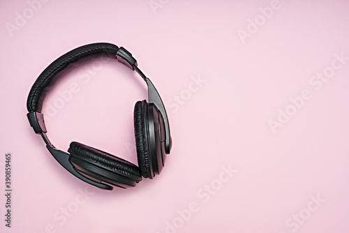 Large, black headphones lie on a colored background. Device for individual listening to music.