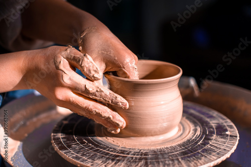 Ceramist master works with clay on a potter's wheel. Artisan production. Close-up. photo