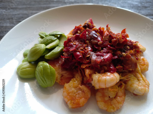 Indonesian food. Fried fresh shrimp with chili shrimp paste on top. Served with petai or stink beans. Very spicy and delicious photo