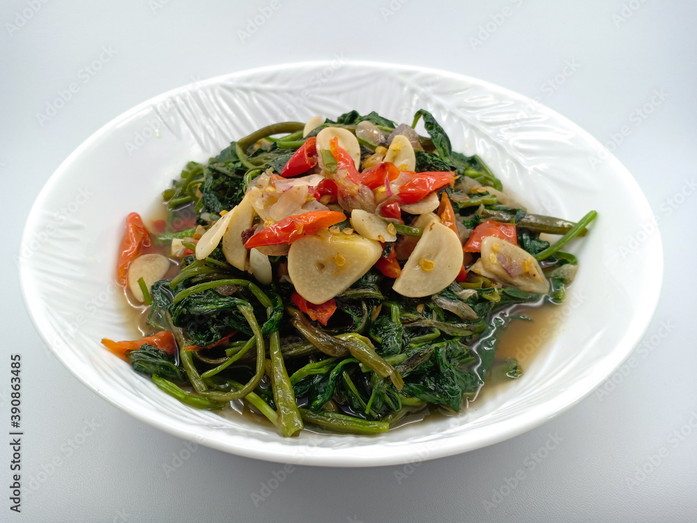 Indonesian healthy food. Sauté water spinach or kale with garlic and red chilli. Water spinach contains good vitamins and garlic as a healthy antioxidant. Vegetarian food menu. Isolated on white Indonesian healthy food. Sauté water spinach or kale with garlic and red chilli. Water spinach contains good vitamins and garlic as a healthy antioxidant. Vegetarian food menu. Isolated on white