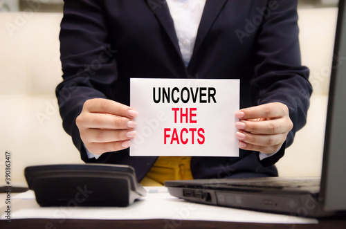 the text uncover the facts is written on a white plate held by a girl