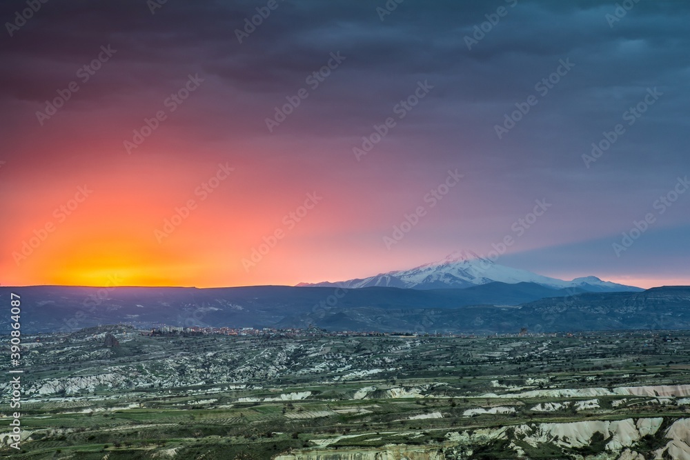 Breathtaking view of Cappadocia valley and amazing sun rising near Erciyes mount.  It is a large stratovolcano that is surrounded by many monogenetic vents and lava domes, and one maar. Turkey.