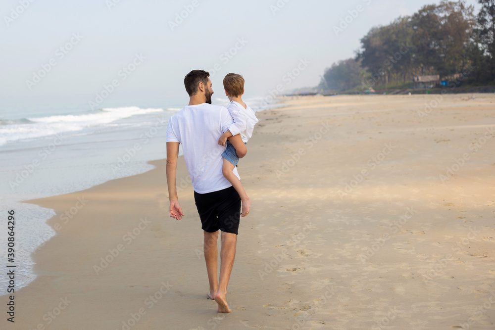 father with son in his arms walking on a tropical beach. India father with son in his arms walking on a tropical beach. India