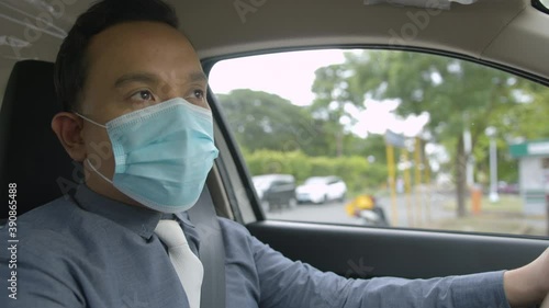 Mid Shot Of A Business Man Wearing A Face Mask While Driving Around The City photo