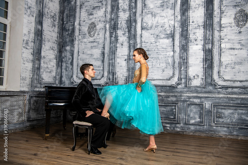 a young man sits at the piano and looks at a dancing partner standing next to him © константин константи