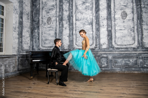 a young man sits at the piano and looks at a dancing partner standing next to him © константин константи