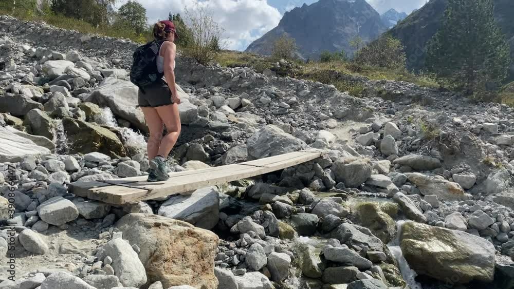 Slow motion shot of a young woman crossing over a small bridge in a beautiful rocky terrain Slow motion shot of a young woman crossing over a small bridge in a beautiful rocky terrain