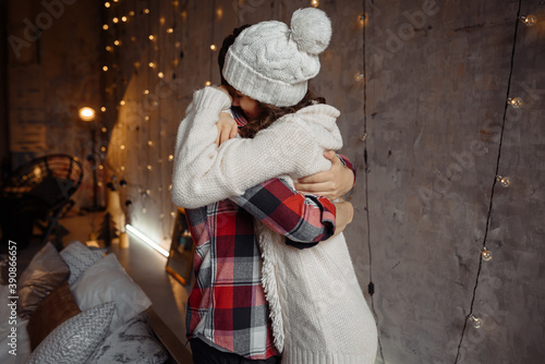 Stylish happy couple hugging each other and spending christmas eve together. Joyful cozy moments in winter holidays. Seasonal greetings. Advertising concept