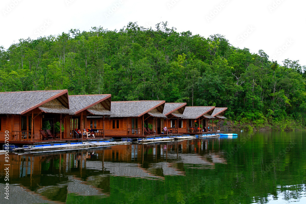 Wooden houses floating on river for tourist take rest and chill out among beauty of nature with green plant mountain at Amadard resort, Kanchanaburi, Thailand. Landmark of Asia travel, Exterior design