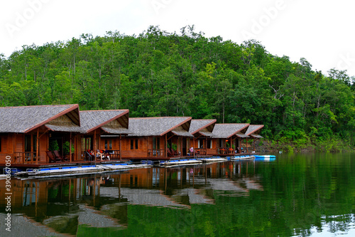 Wooden houses floating on river for tourist take rest and chill out among beauty of nature with green plant mountain at Amadard resort, Kanchanaburi, Thailand. Landmark of Asia travel, Exterior design © Nattasak