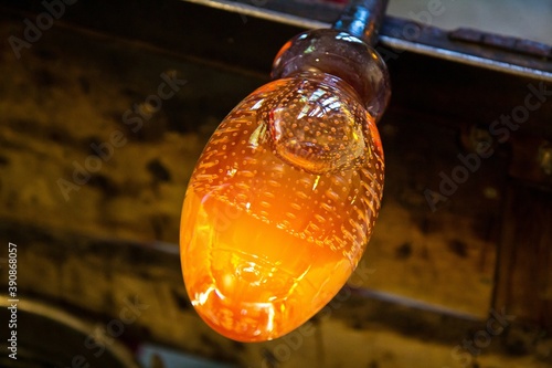 Closeup view of future handmade glass figure at the end of glassblowing pipe. It is still very hot. Glassblower workshop. Helsinki, Finland.