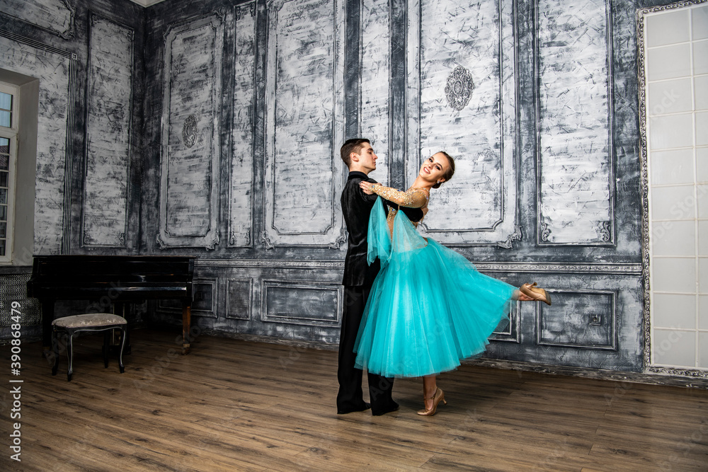young couple in evening dance costumes dancing tango in the ballroom