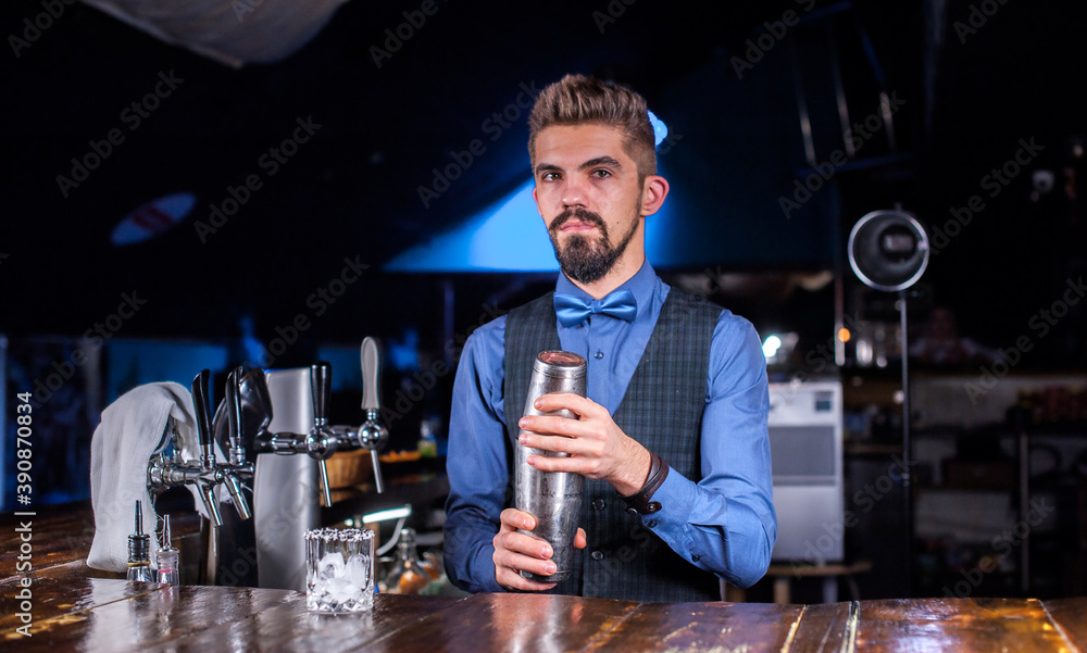 Experienced barman demonstrates the process of making a cocktail while standing near the bar counter in pub Experienced barman demonstrates the process of making a cocktail while standing near the bar counter in pub