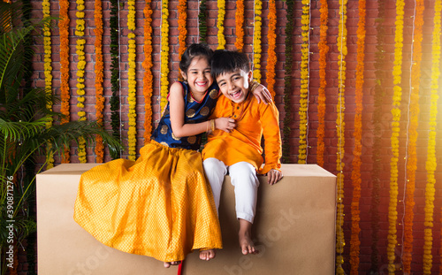 Indian asian cute little kids or siblings celebrating Diwali with gifts and sweet laddoo photo