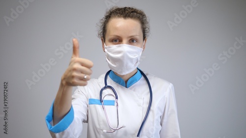 Healthcare system advice during pandemic outbreak. Thumbs up from female medical worker for wearing face mask to protect public from catching coronavirus
