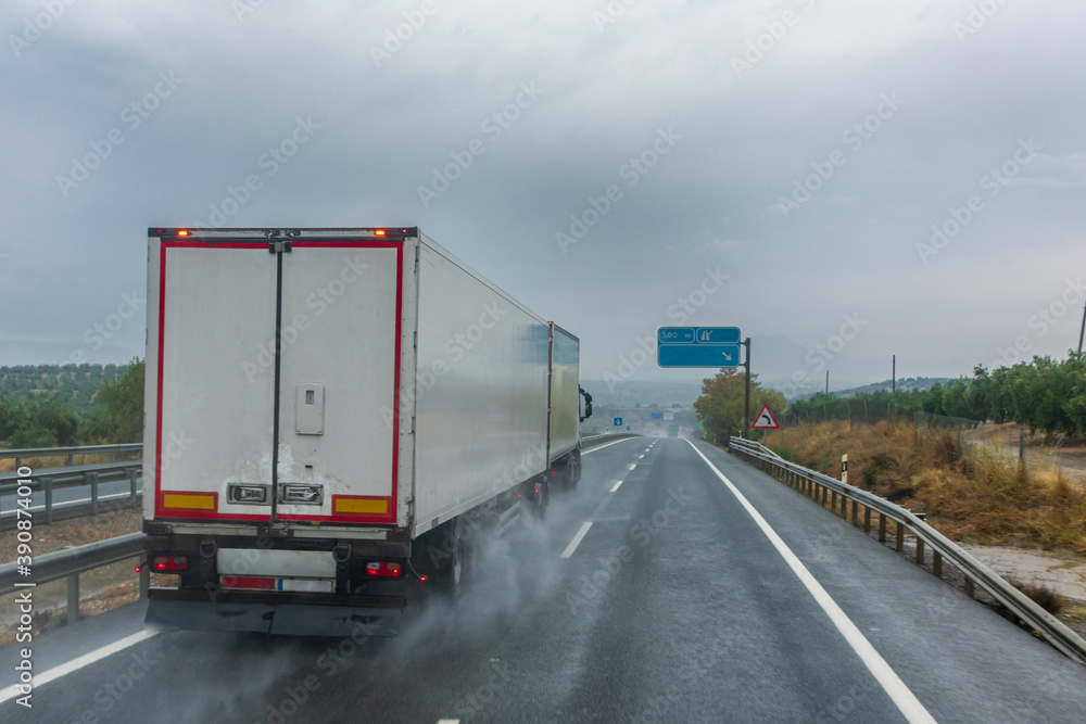 Truck with modular euro configuration driving on a highway on a rainy day.