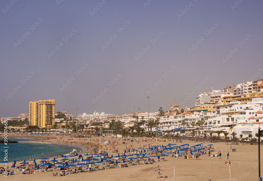Sun worshippers and visitors enjoying the sunshine on the beach at Los Cristianos, Teneriffe, Canary Islands, Spain