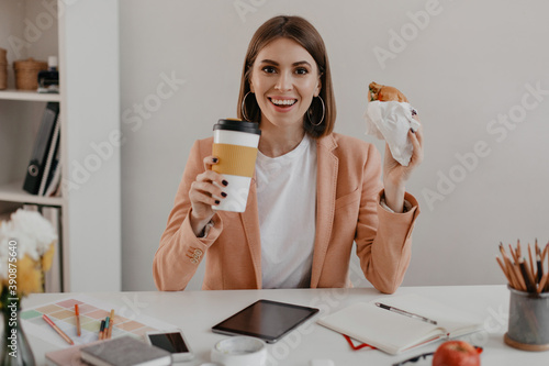 Joyful business woman looking at camera with smile while having lunch in bright office