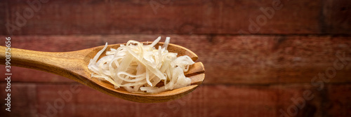 sauerkraut (fermented cabbage) on a wooden spoon against rustic barn wood background, probiotics concept - fermented food good for gut health, panoramic web banner