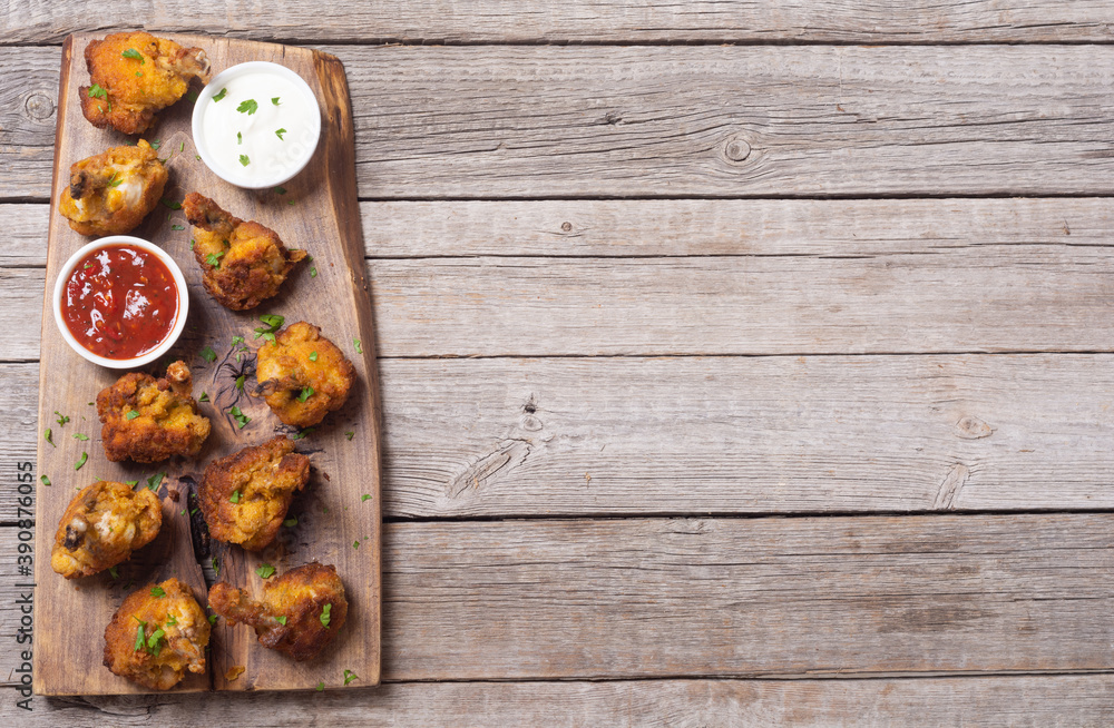 Fototapeta premium Chicken wings nuggets with sauces on wooden background .