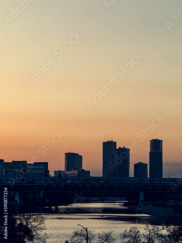 Evening industrial cityscape. River in the foreground, in the background the sky sunset and high-rise buildings