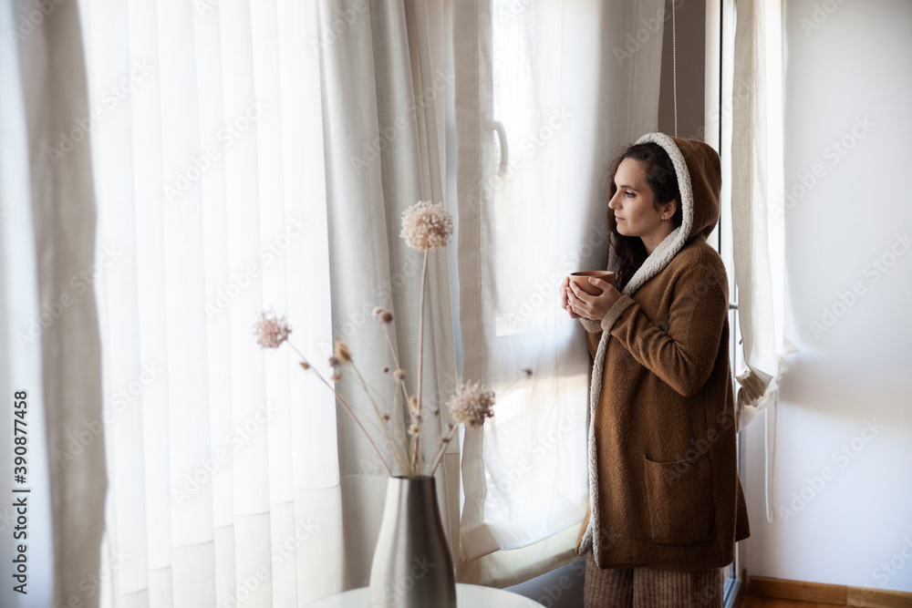 Girl with a cup of coffee in front of the window in winter. Girl with a cup of coffee in front of the window in winter.