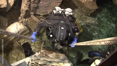Speleodivers in diving suits descend into a cave lake, from which an underwater hole leads to the Orda underwater cave.