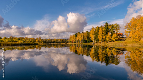 panoramic colorful landscape with beautiful clouds and trees in the lake, gorgeous trees by the pond, golden autumn