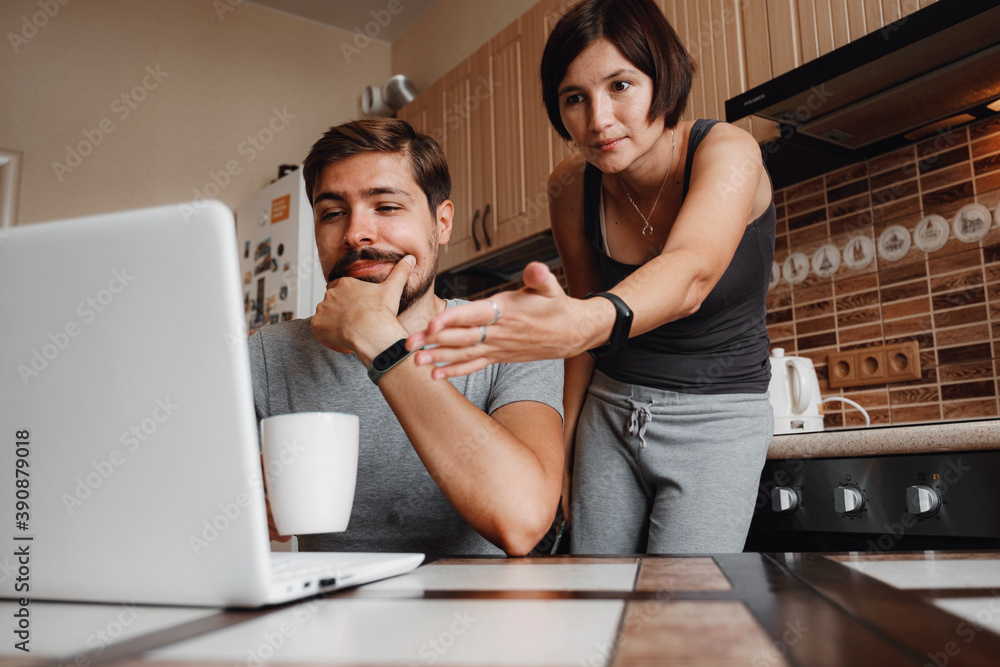 Couple at kitchen, reading news and using laptop. Couple at kitchen, reading news and using laptop.