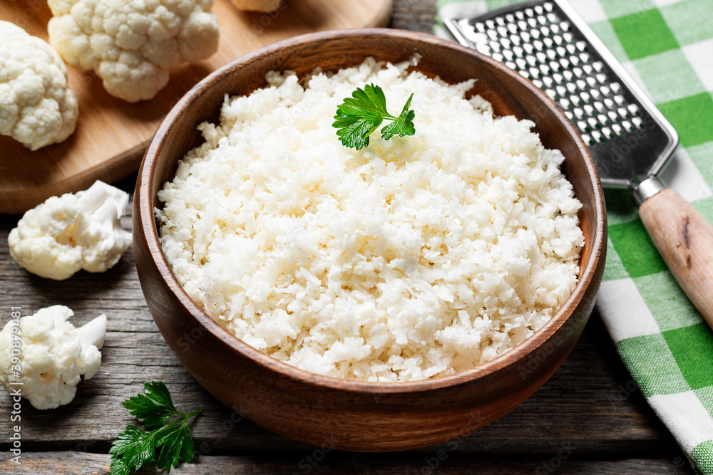 Freshly grated raw cauliflower rice in wooden bowl Freshly grated raw cauliflower rice in wooden bowl