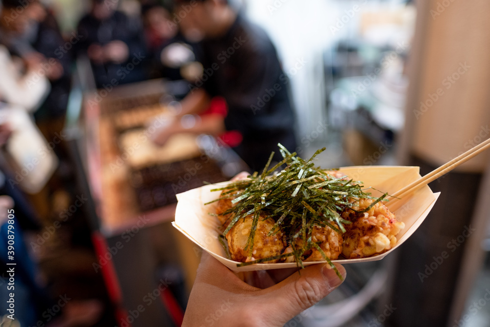 Naklejka premium Holding a boat of Teppanyaki Balls with seaweed on top, street food, osaka, japan, December 17, 2018