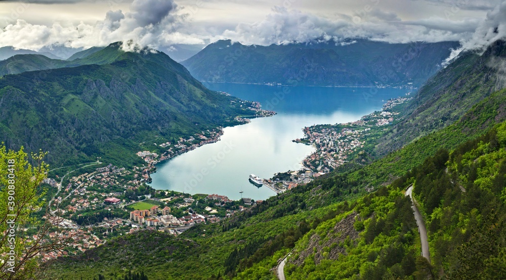 Picturesque view of the Bay of Kotor: mountains covered with forests surround small towns in the lowland in Montenegro.