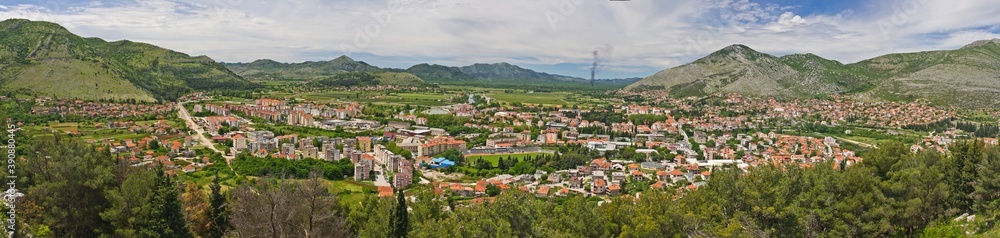 The aerial view on old Trebinje city in the lowland surrounded with mountains in summer against cloudy sky in Bosnia and Herzegovina.