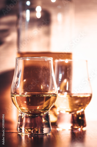 Selective focus glasses of whiskey on rustic wood background, Alcohol drink whiskey or bourbon with ice cubes on wood table together while at bar counter in the pub.