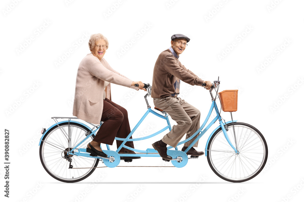 Elderly man and woman riding a blue tandem bicycle and looking at camera Elderly man and woman riding a blue tandem bicycle and looking at camera